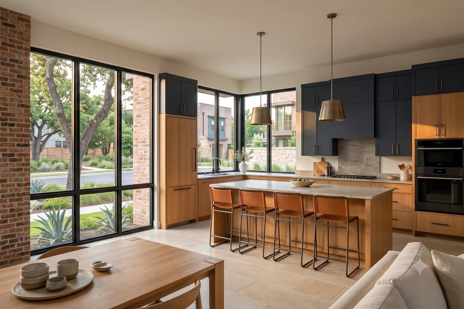 An open-plan kitchen with navy upper cabinets, oak lowers, a stone island with four leather stools and windows on two sides