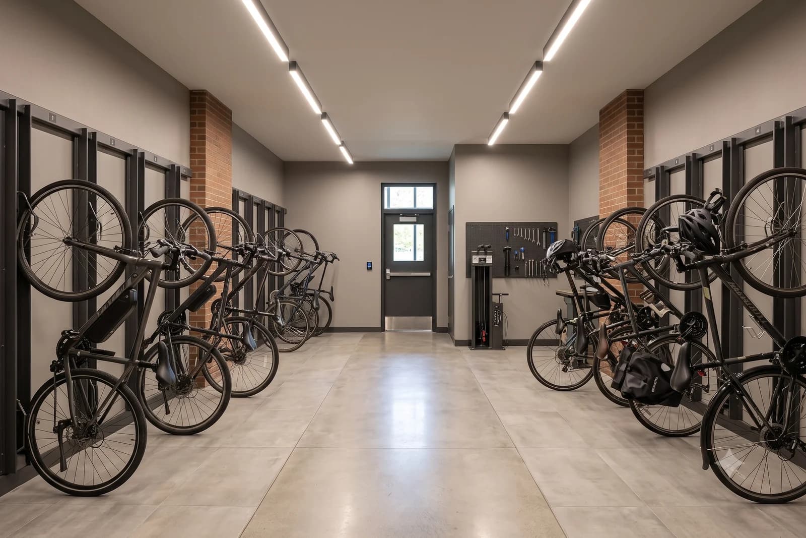 The bike storage room off the lobby, bicycles on wall racks along both walls with a repair stand and tool board at the far end